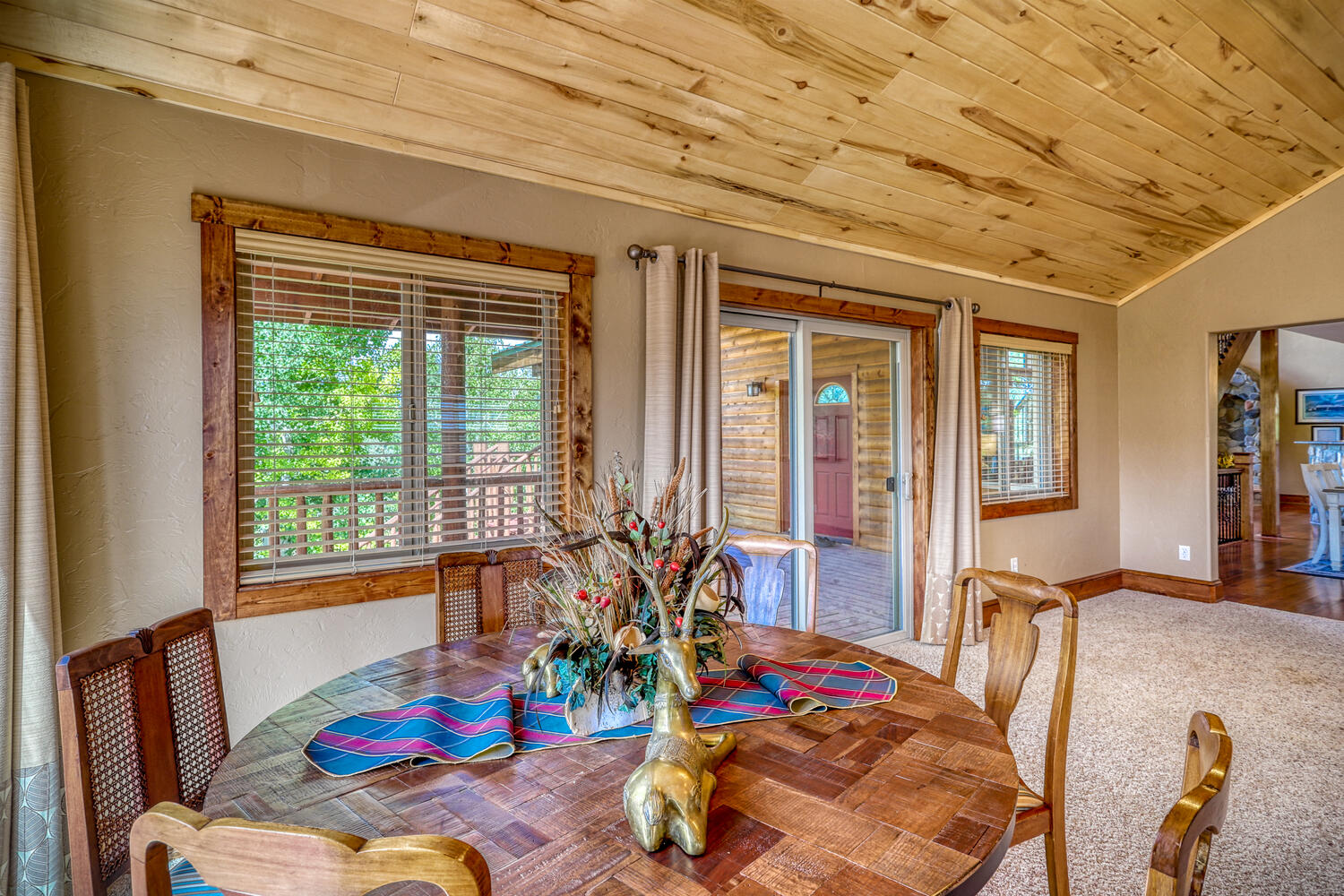 Large family room with sofas, table seating, and flat-screen TV in Eagle's View with view of large wrap-around porch